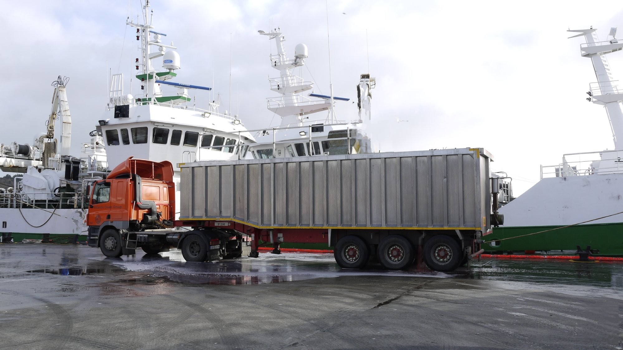 lorry with trailer parked pierside next to fishing vessel